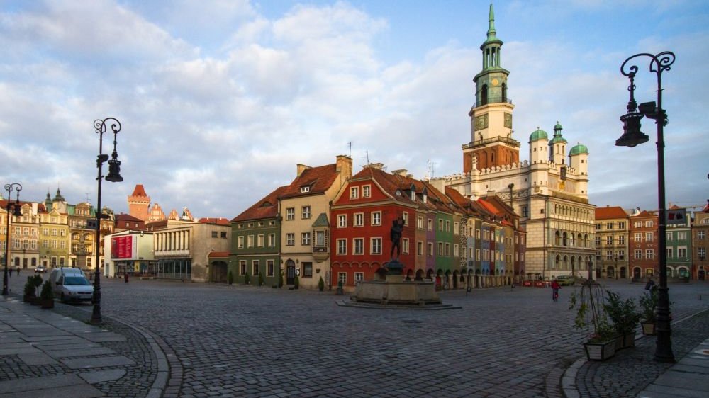 Centrum Starego Rynku z daleka - widać zabytkowe kamienice otaczające ratusz oraz brukowane uliczki. Zdjęcie zrobione w pogodny dzień, niebo jest błękitne.