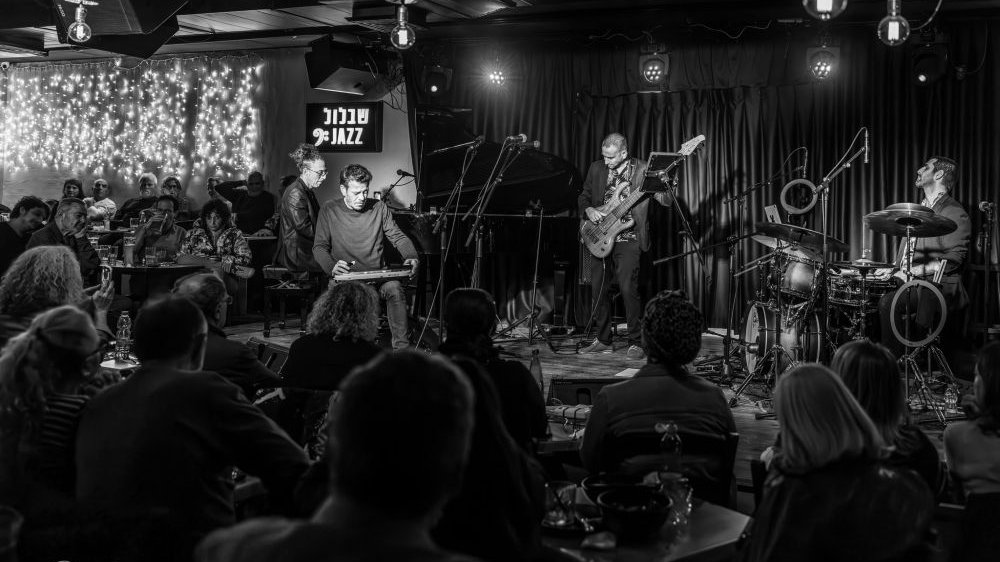 Muzycy na scenie w klubie jazzowym grają koncert przed publicznością.