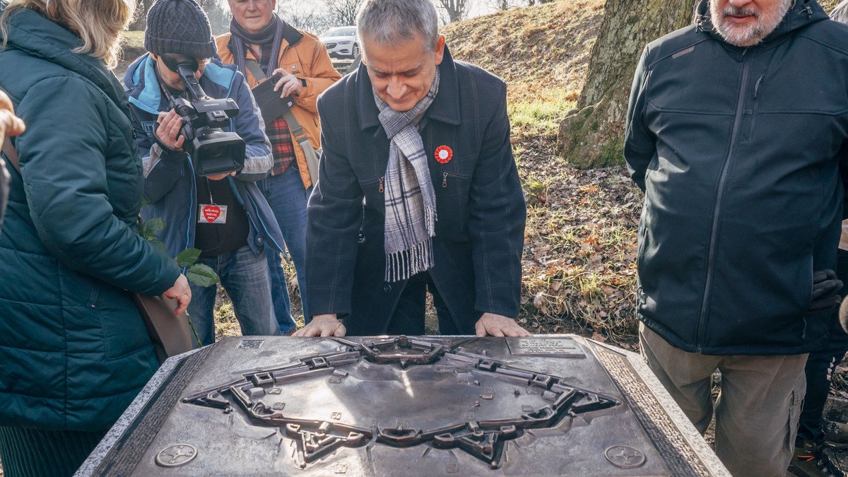 Mężcyzna w płaszczu, otoczony przez obserwatorów, patrzy na metalową makietę Cytadeli