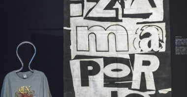 Czarno-biały plakat zespołu Pidżama Porno na ścianie i wisząca na manekinie krawieckim niebieska koszulka z nadrukiem przedstawiającym ludzkie serce.
