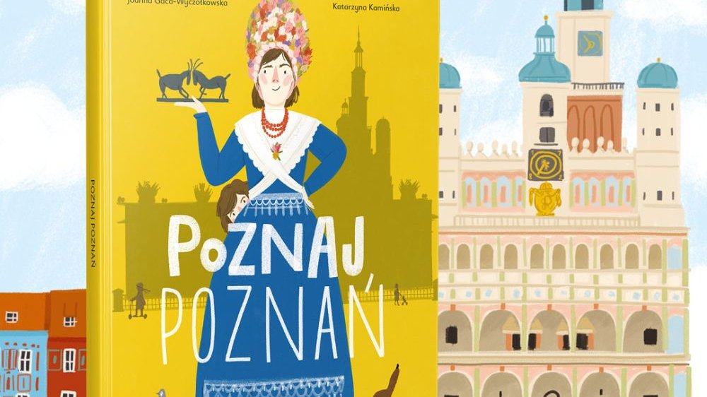 Okładka "Poznaj Poznań", na której występuje narysowana, dumna bamberka w niebieskiej sukni i czepcu na głowie, w jednej ręce trzyma trykajace się koziołki. Obok niej stoi jamnik oraz gołąb. Za okładką widać narysowany poznański ratusz.