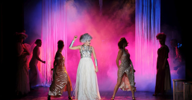 Atena tańczy na środku, wokół niej pozostałe boginie, scena jest pokrywa różową mgłą, a Atena ma bojowy wyraz twarzy.