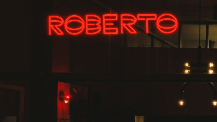 Krwistoczerwony neon "Roberto" świeci w ciemności.