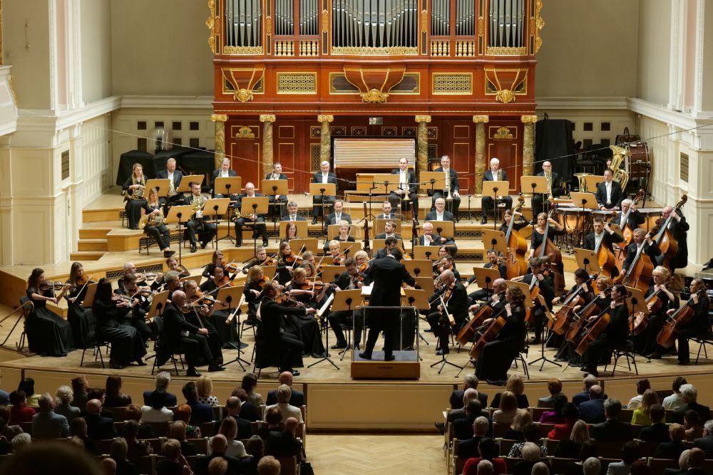 Muzycy filharmonii występują na scenie. Pod sceną publiczność, za sceną ogromne drewniane organy. - grafika artykułu