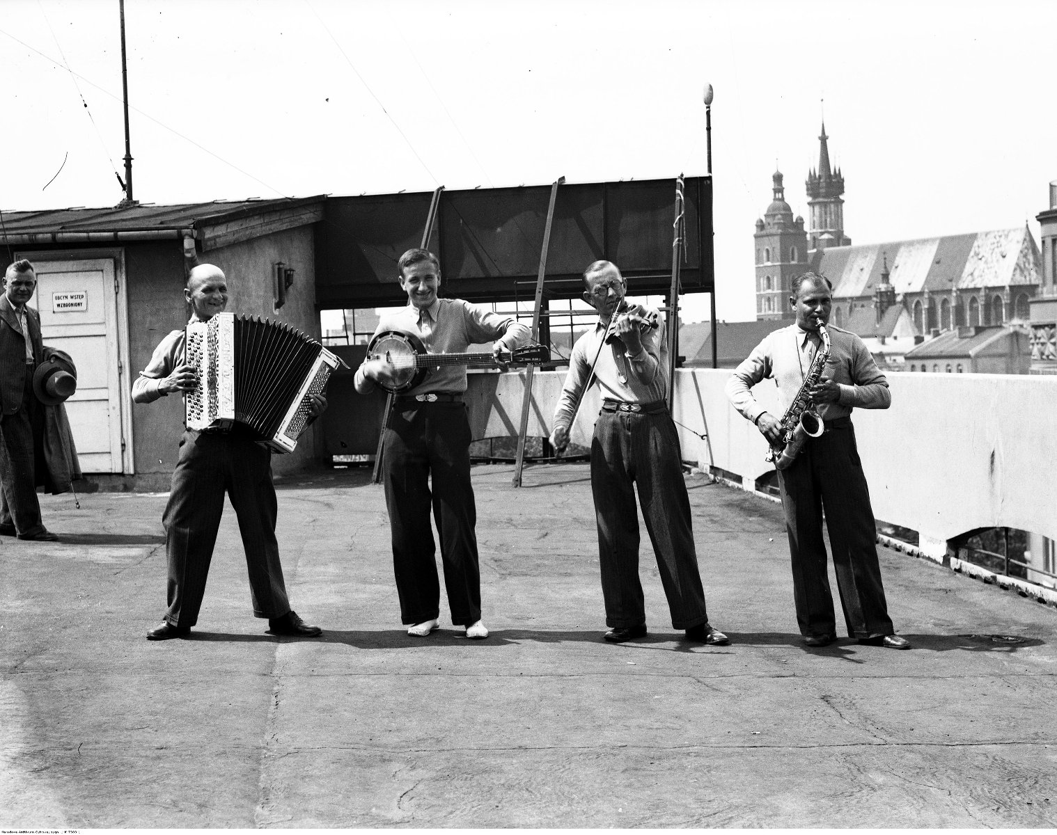 W centrum czarno-białej fotografii jest czterech mężczyzn w średnum wieku z instrumentami muzycznymi. Mają eleganckie spodnie i koszule. Są w dobrym nastroju. - grafika artykułu