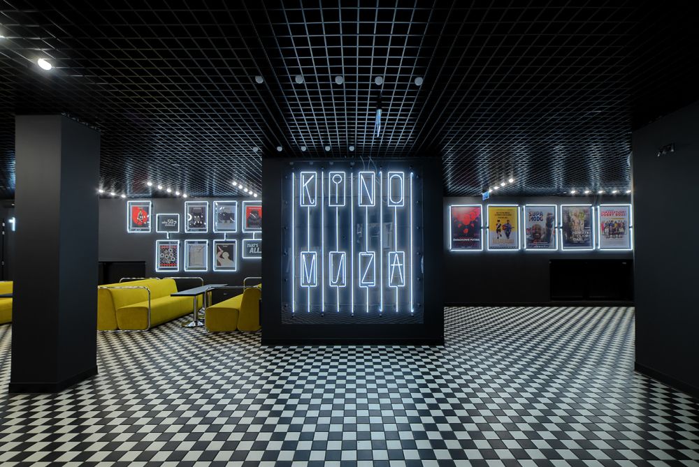 Hol kina Muza z jasno świecącym neonem i czarno-białą posadzką w szachownicę. - grafika artykułu