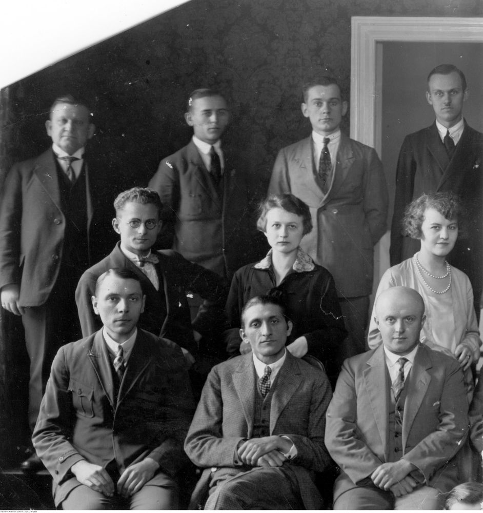 Czarno-białe zdjęcie grupowe elegencko ubranych kobiet i mężczyzn. Część grupy stoi, część siedzi. - grafika artykułu