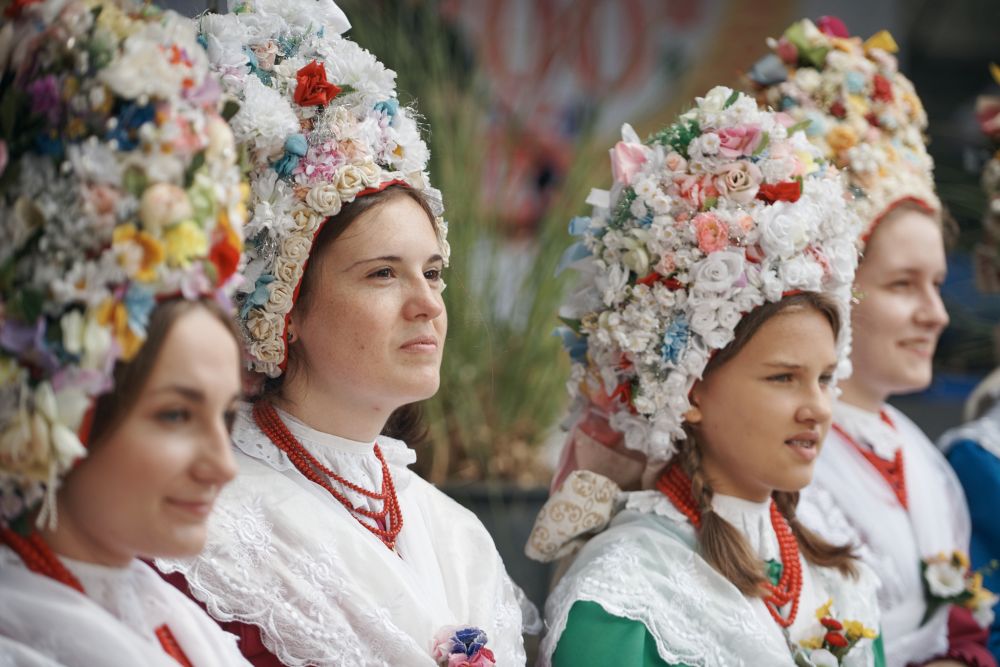 Młode kobiety w tradycyjnych strojach bamberskich, z kolorowymi karnetami z kwiatów na głowach. - grafika artykułu