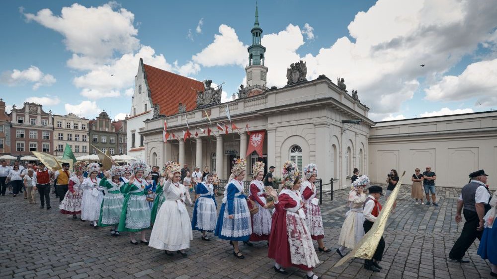 Pochód bamberski przechodzi przez Stary Rynek w Poznaniu. Za ludźmi widoczny budynek Odwachu z powiewającymi flagami.