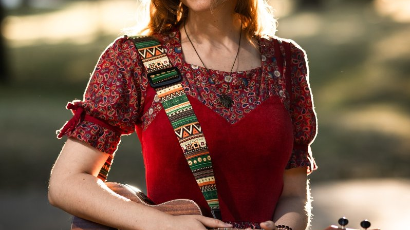 Dziewczyna w czerwonej, folkowej sukience z ukulele (miniaturową gitarą)