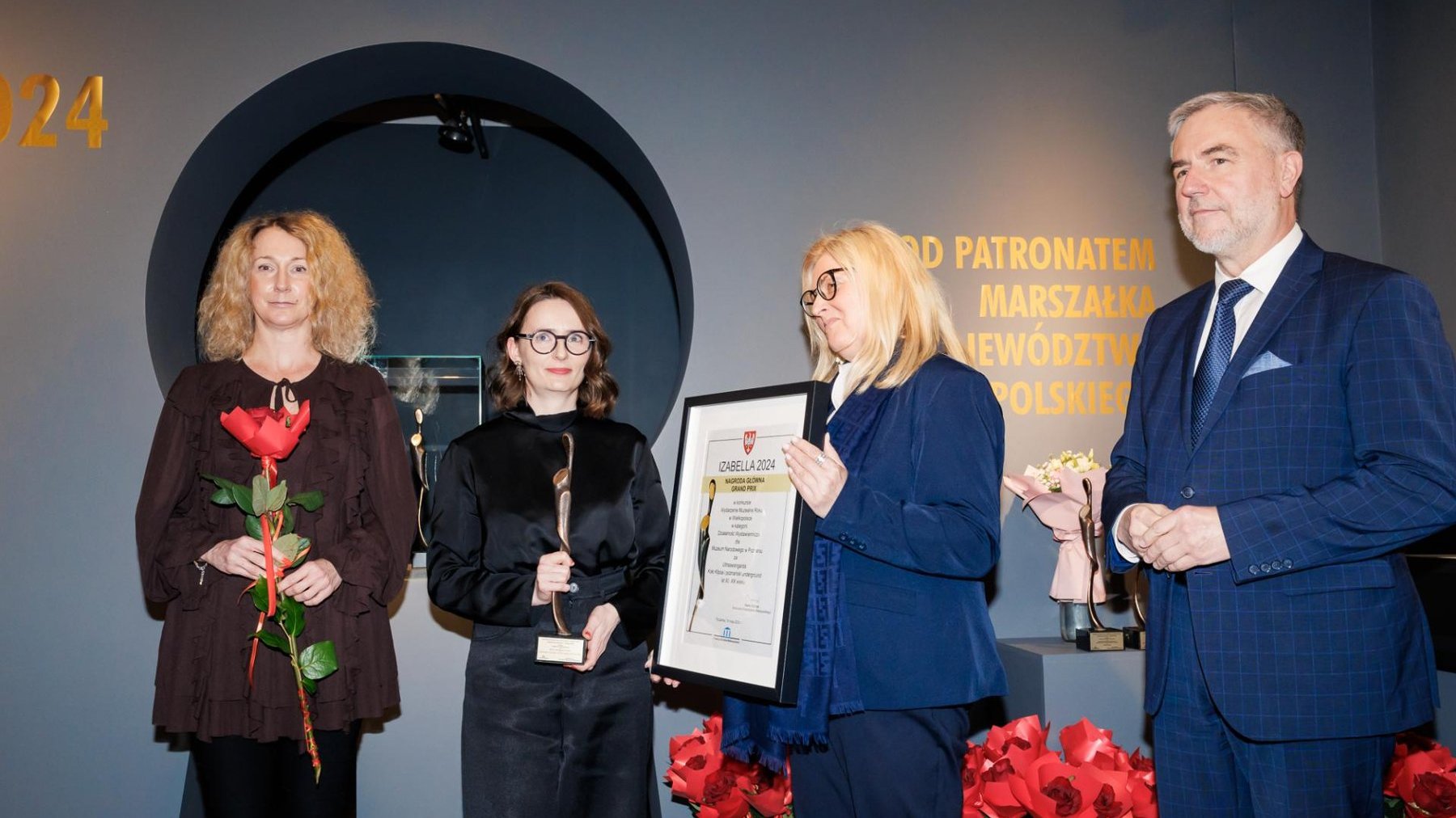 Laureatki odbierają nagrody, w rękach kwiaty, statuetka, obok wręczający