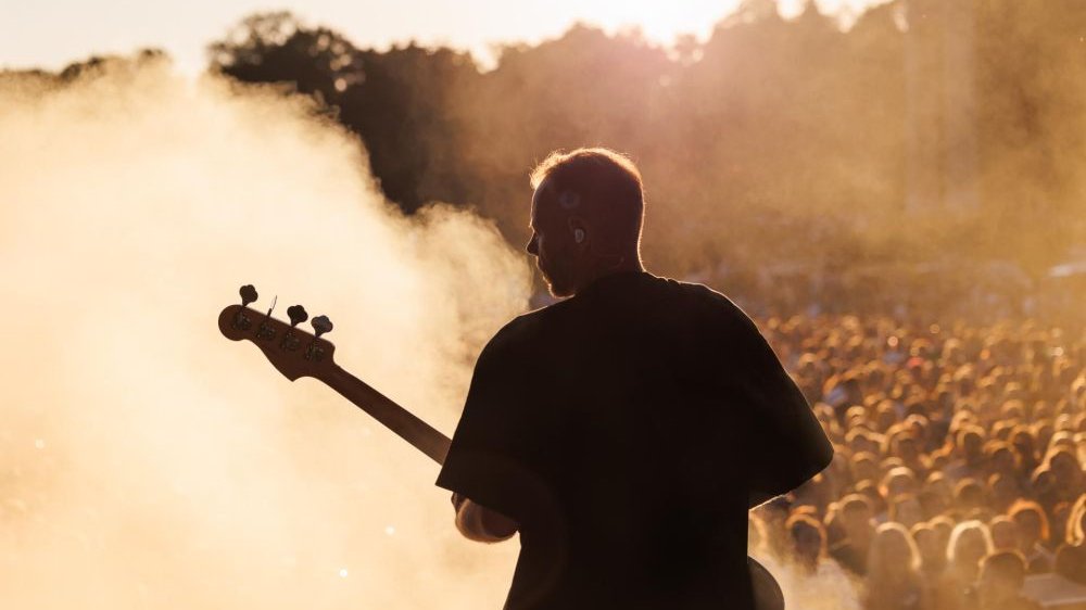 Gitarzysta na plenerowej scenie podczas występu.