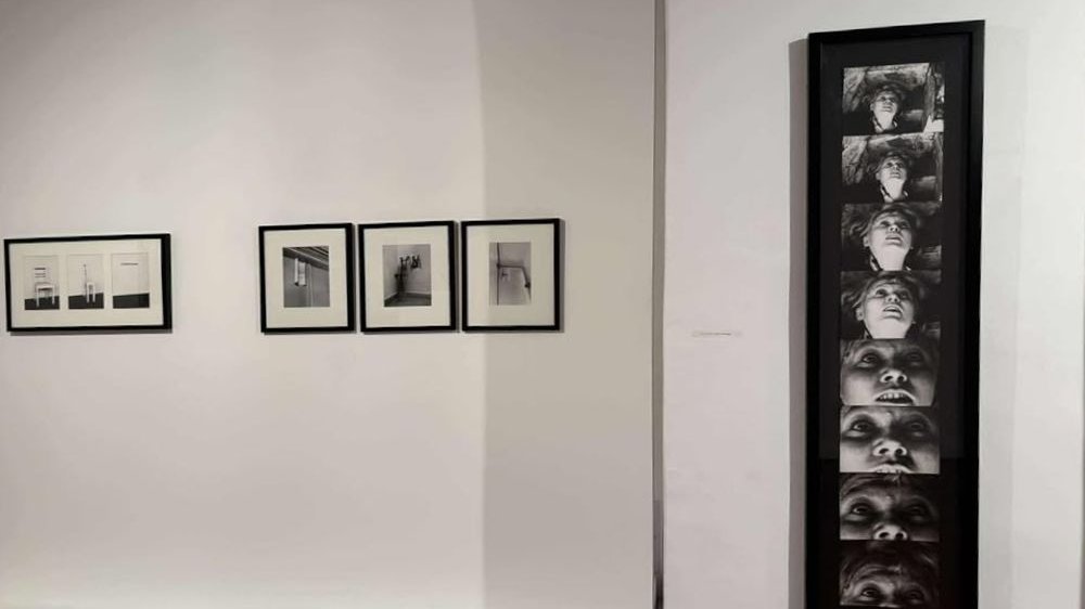Czarno-białe fotografie na białej ścianie galerii.