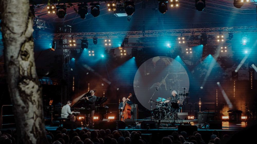Plenerowy koncert po zmroku, scenę oświetlają reflektory.