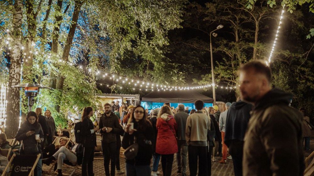 Tłum na terenie festiwalu. Jest wieczór, ale dookoła dużo drzew i światełek.