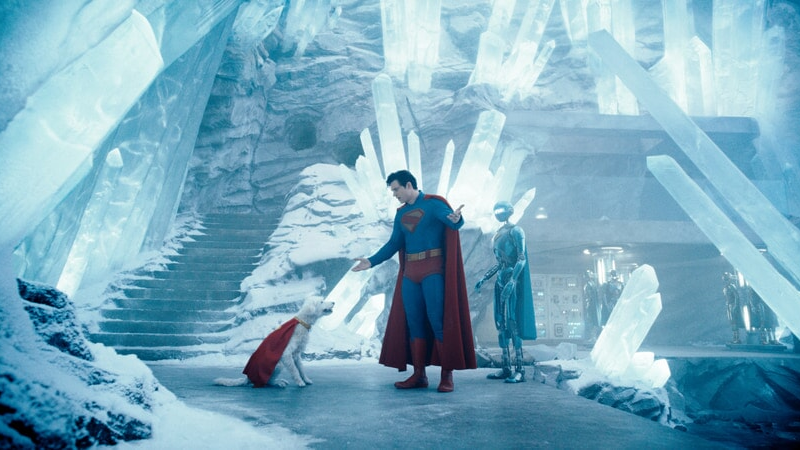 Superman z superpsem w lodowej jaskini. Obok nich robot.