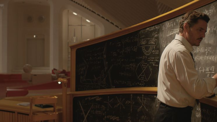 Mężczyzna w białej koszuli dokonuje obliczeń matematycznych na dużej tablicy.