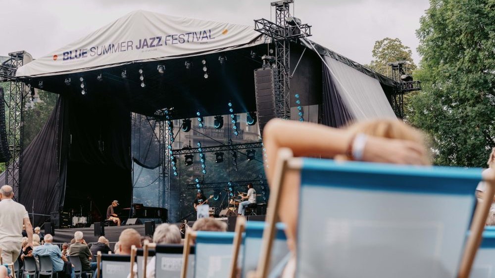 Koncert zespołu na scenie. Publiczność pod sceną siedzi na leżakach.