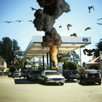 Obrazek przedstawia sztuczne wyuchy na stacji benzynowej położonej na obrzeżach miasta. Dookoła latają ptaki. Wybuchy i ptaki wyglądają jakby były zrobione w paint-cie.