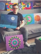 Tomasz Włodarczyk na kanapie z obrazami.