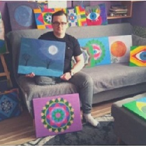 Tomasz Włodarczyk na kanapie z obrazami.