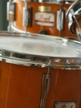 Na obrazku widać trzy bębny od perkusji w kolorze biało-pomarańczowym.