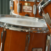 Na obrazku widać trzy bębny od perkusji w kolorze biało-pomarańczowym.