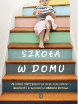 Dziecko siedzące na kolorowych schodach i trzymające książkę w ręku.