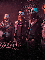 Zdjęcie na którym widać czterech członków zespołu. W lewym dolnym rogu napis z nazwą zespołu Dopelord.