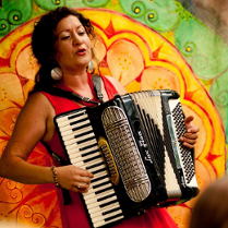 Artystka z akordeonem na kolorowym tle.