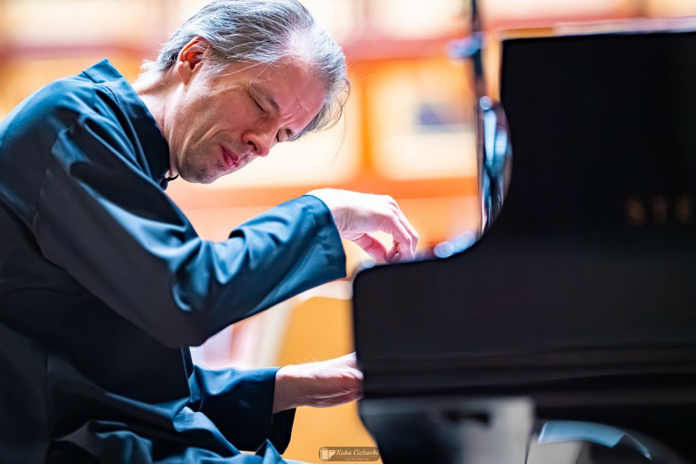 Pianista gra z zamkniętymi oczami, w pełnym skupieniu.