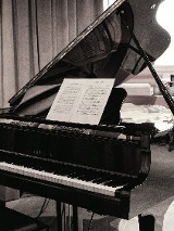 Czarno-białe zdjęcie fortepianu, na którym rozłożono nuty.