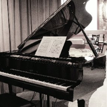 Czarno-białe zdjęcie fortepianu, na którym rozłożono nuty.