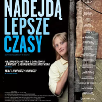 Młoda dziwczyna o blond włosach, w żółtej koszuli. Wychyla się zza wejścia do budynku.