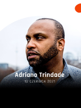 Adriano Trindade patrzy w dal, w tle miasto.