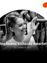 Uśmiechnięta kobieta z ręką w górze. W tle widownia.