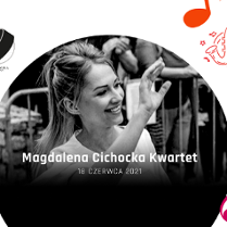 Uśmiechnięta kobieta z ręką w górze. W tle widownia.