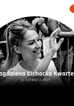 Uśmiechnięta kobieta z ręką w górze. W tle widownia.