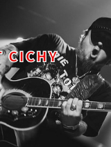 Robert Cichy gra na gitarze na scenie, ma otwartą buzię.