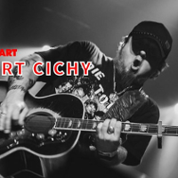 Robert Cichy gra na gitarze na scenie, ma otwartą buzię.