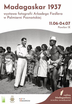Plakat z czarno-białym zdjęciem Arkadego Fiedlera w otoczeniu mieszkańców Madagaskaru.