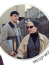 .Kobieta i mężczyzna w czapkach i płaszczach. Za nimi budynki.