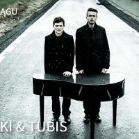 Dwóch mężczyzn ubranych na czarno, stoją na ulicy za małym fortepianem.