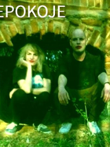 Kobieta i mężczyzna kucają przy murze. Mają pomalowane na czerwono usta.