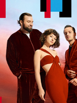 Czworo artstów (trzech męzczyzn i jedna kobieta) elegancko ubrani w odcienie czerwieni pozuja do zdjęcia na tle nieba w odcieniach czerwieni, pomarańczu i niebieskiego po zachodzie słońca.