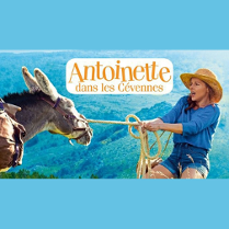 Młoda kobieta ciągnie osła na sznurku. W tle widać góry.