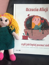 Okładka książki Ewy Woydyłlo i kolorowa lalka robiona na szydełku.