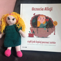 Okładka książki Ewy Woydyłlo i kolorowa lalka robiona na szydełku.