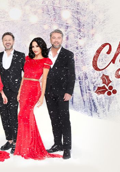 Trzech mężczyzn w garniturach oraz dwie kobiety w czerownych sukienkach pozują na tle śnieżnego lasu. Obok czerowne napisy.