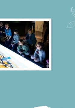 Dziei ogladające prezentacje multimedialne w sali muzealnej.